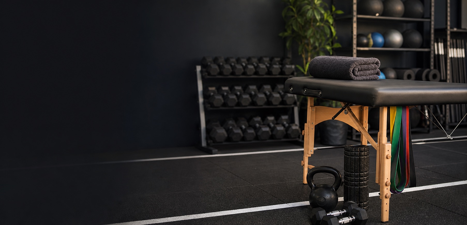 Sports massage table and strength training equipment in a gym recovery room